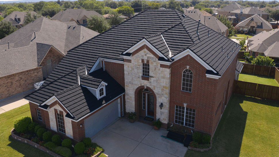 Aerial view of brick home with Hurricane Shake Pro | US Metal Roofing Consortium Aerial view of two-story brick house with black Hurricane Shake Pro metal roof.