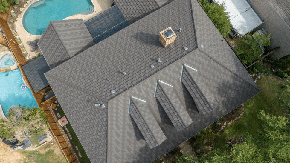 Aerial View of Durable Metal Roof | US Metal Roofing Consortium Drone view of a large home's dark metal roof and backyard pools