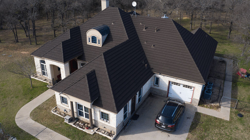 Aerial view of home with dark metal roof | US Metal Roofing Consortium Aerial view of a large house with dark brown metal roof and driveway.