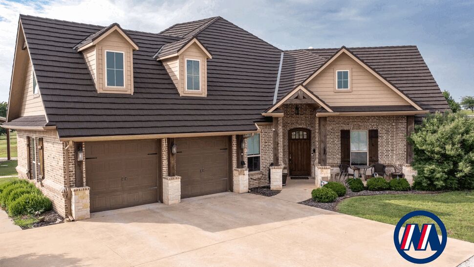 Dark metal roof on brick home | US Metal Roofing Consortium Brick suburban home with dark metal roof, two-car garage, and landscaped front yard