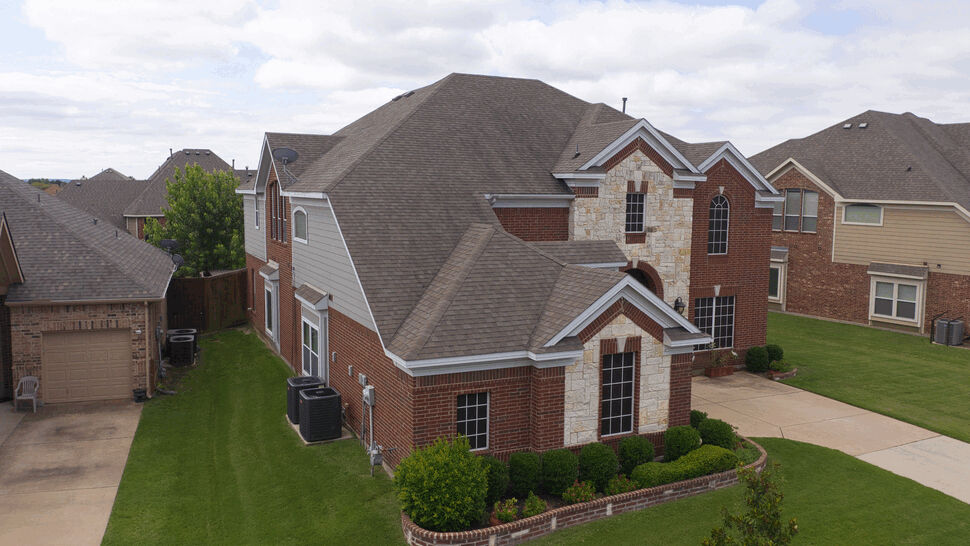 Side aerial recommending Hurricane Shake Pro | US Metal Roofing Consortium Aerial side view of a multi-gabled brick house roof and surrounding lawns.