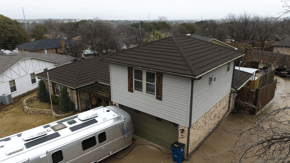 House with a brown metal roof and a silver trailer parked in driveway