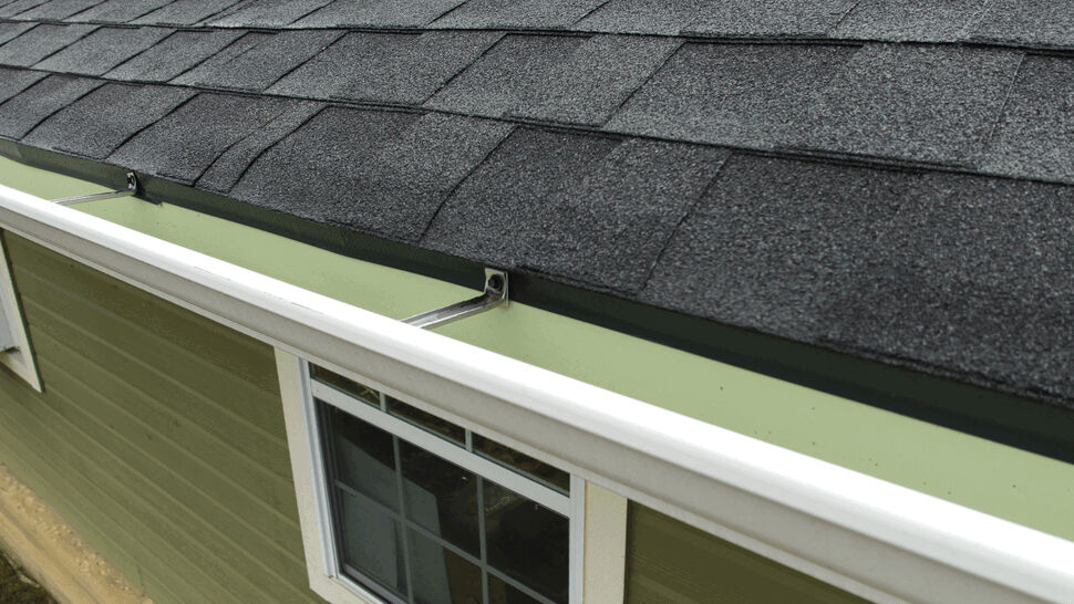 Edge detail of black stone-coated metal shingles and a rain gutter.