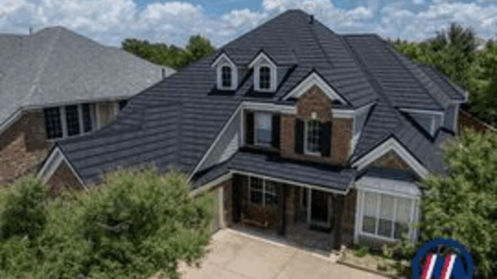 Suburban brick home with dark stone-coated metal roof and driveway