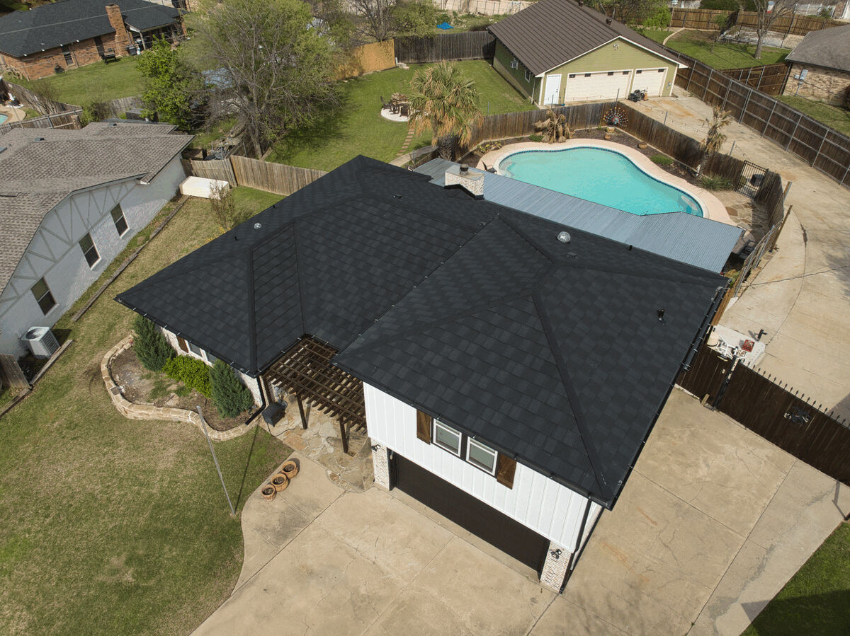 Aerial view of a house with a black roof and backyard pool