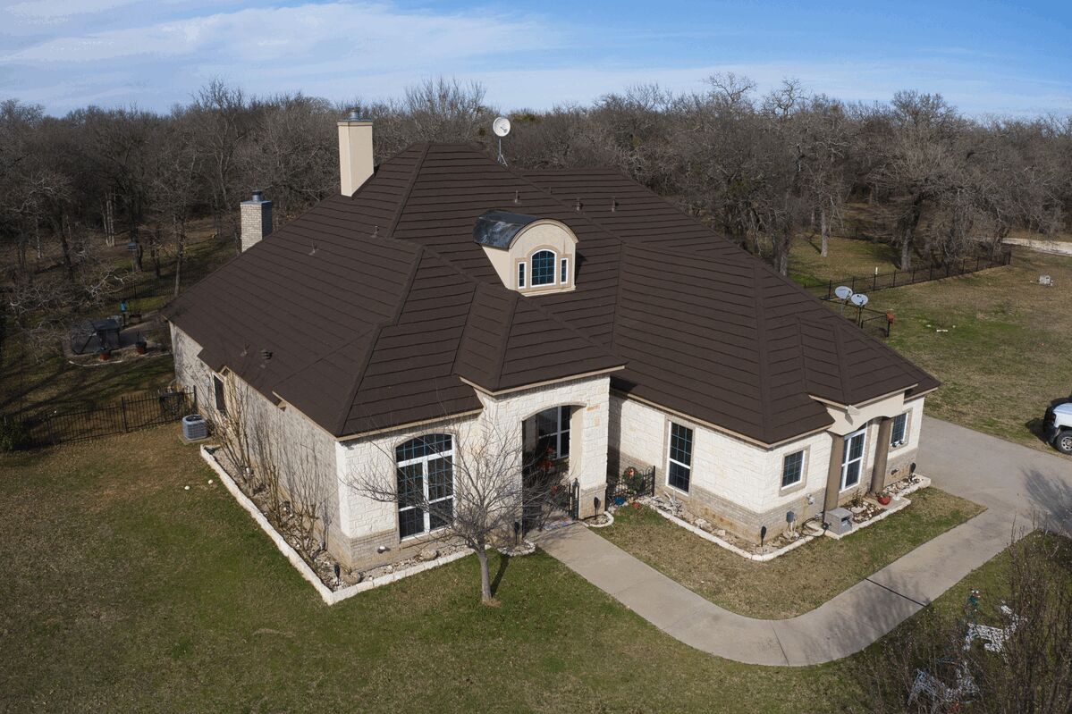 Aerial view of a house with a dark brown metal tile roof.