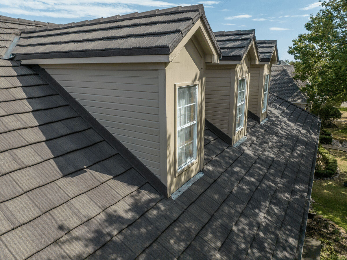 Close view of dark metal shake roof with dormer windows