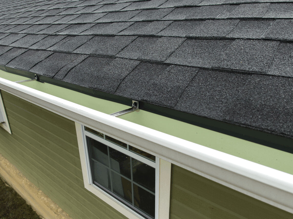 Edge detail of black stone-coated metal shingles and a rain gutter.