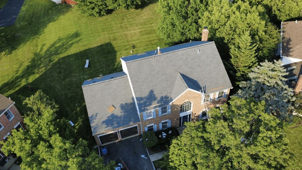 Aerial shot of a finished roof with ladder in place for final inspection.