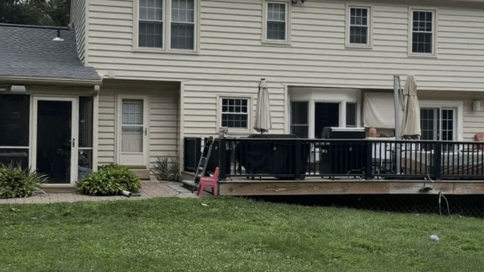 Rear view of house showing a completed new gray shingle roof above the backyard deck.