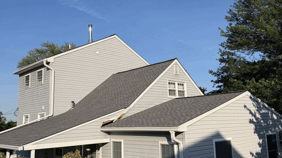 Rear view of house showing a newly installed gray shingle roof and clean rooflines.