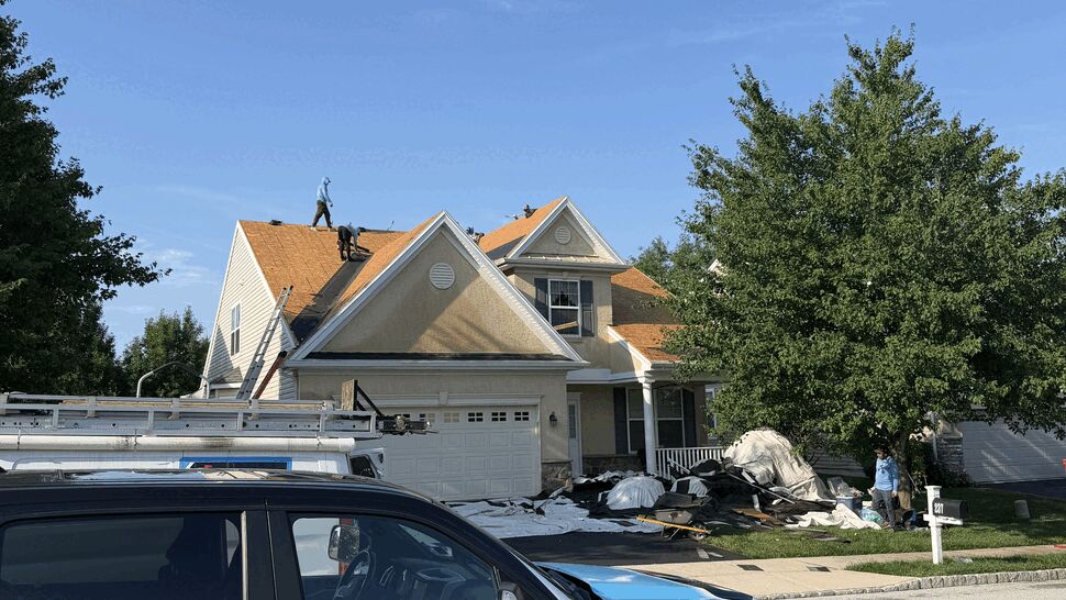 Paramount Home Solutions vehicle with roofers removing old shingles and piled debris.