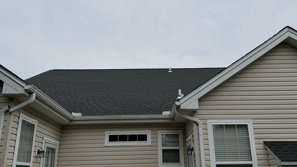 Back patio with new dark shingles and visible white gutters installed.