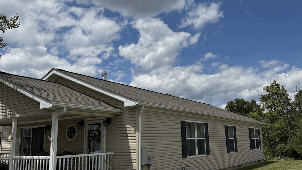 Front porch of a beige house with visible gutters, roof shingles and siding.
