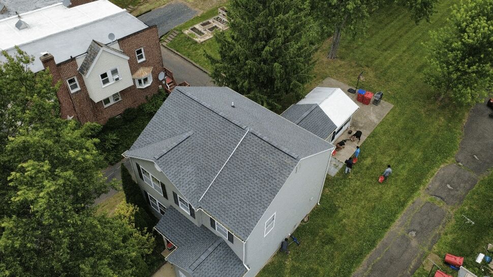 Top-down drone view of a completed roof with visible gutters around a suburban house.