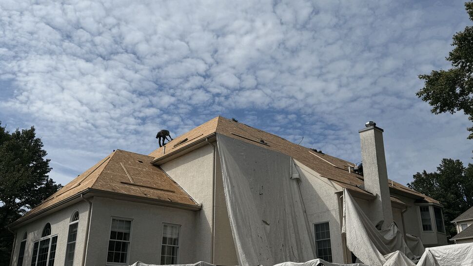 Large home with roof stripped and protective tarps draped over deck