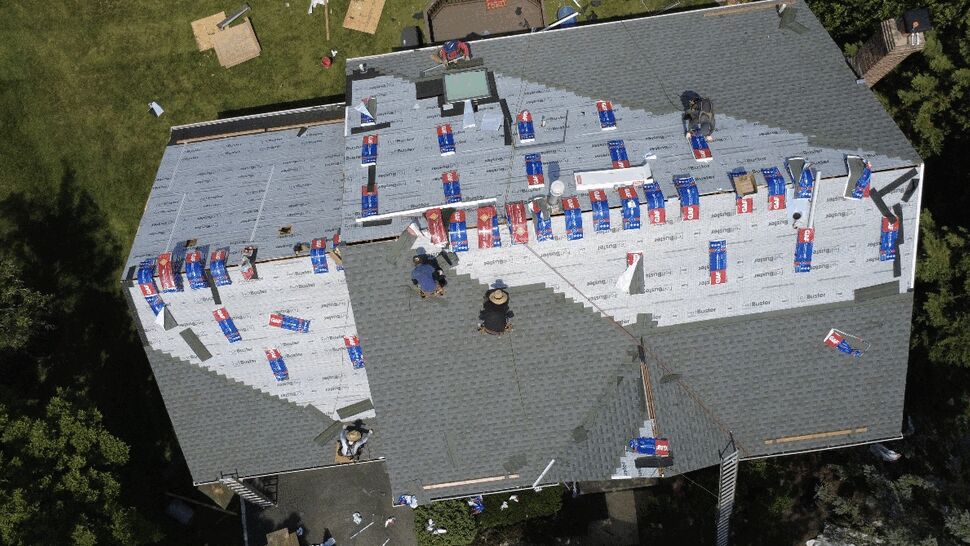 Top-down view of roof underlayment and bundled shingle packages ready for installation.