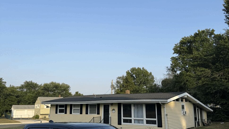Paramount Home Solutions pickup in front of a yellow sided house under a blue sky.