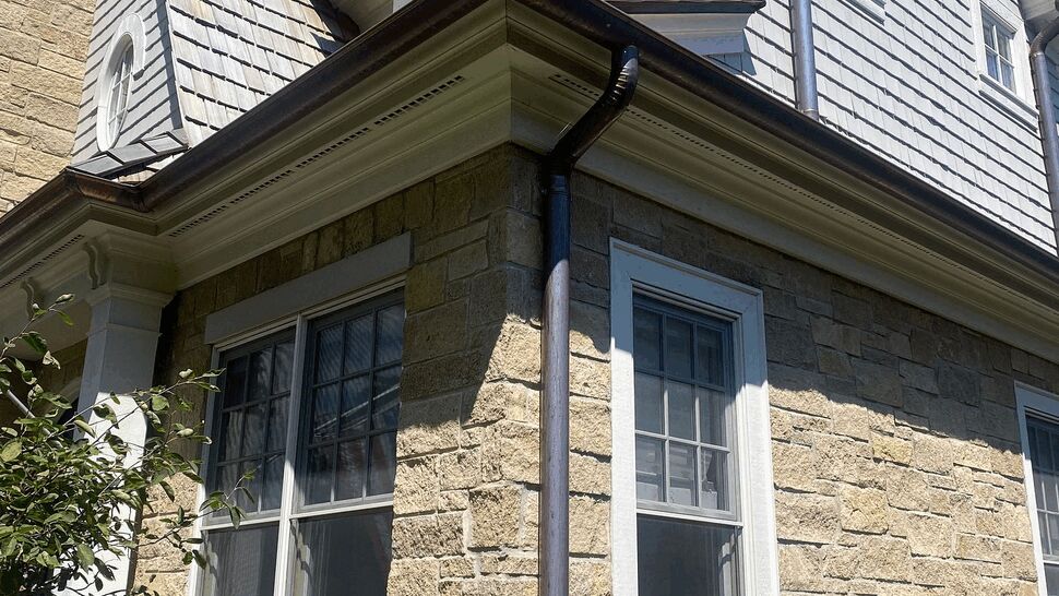 Stone Siding with Downspout | C&N Construction Stone lower wall with shingle siding and vertical metal downspout