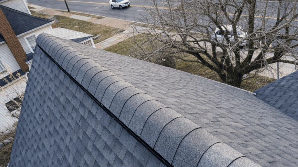 Asphalt Roof Ridge Inspection | Tycos Roofing And Siding Inc Close-up view of gray asphalt shingle ridge on a residential roof.