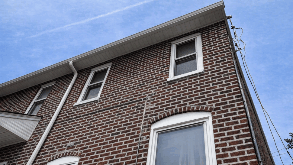 Roofline and Gutters Close-up | Tycos Roofing And Siding Inc Close-up of brick facade showing roofline, gutters, and second-floor windows.