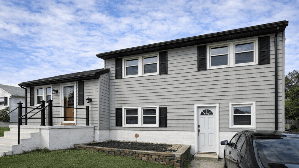 Gray Siding and Windows | Tycos Roofing And Siding Inc Gray-sided home with black shutters, white windows, and front steps.