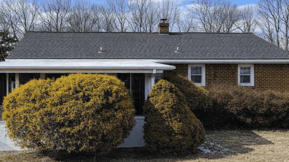 Brick ranch roof with asphalt shingles | Tycos Roofing And Siding Inc Brick ranch house with dark asphalt shingle roof under a blue sky and clouds.