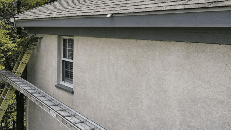 Ladder and tools on roof edge near eave for gutter work