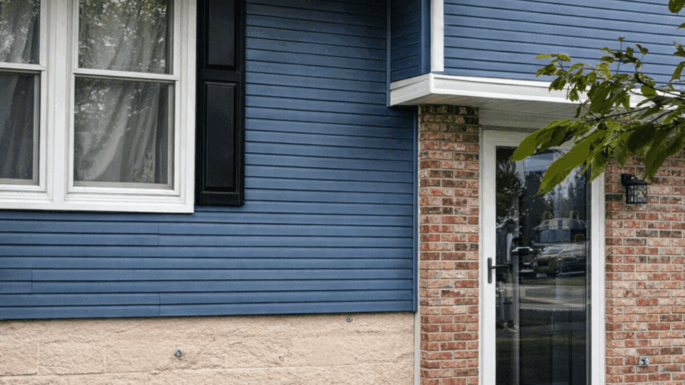 Blue Siding Entryway | Tycos Roofing And Siding Inc Blue siding, white windows, and a glass entry door on a brick home.