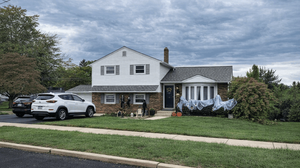 Front exterior of split-level home with grey roof, white siding, and a small lawn.