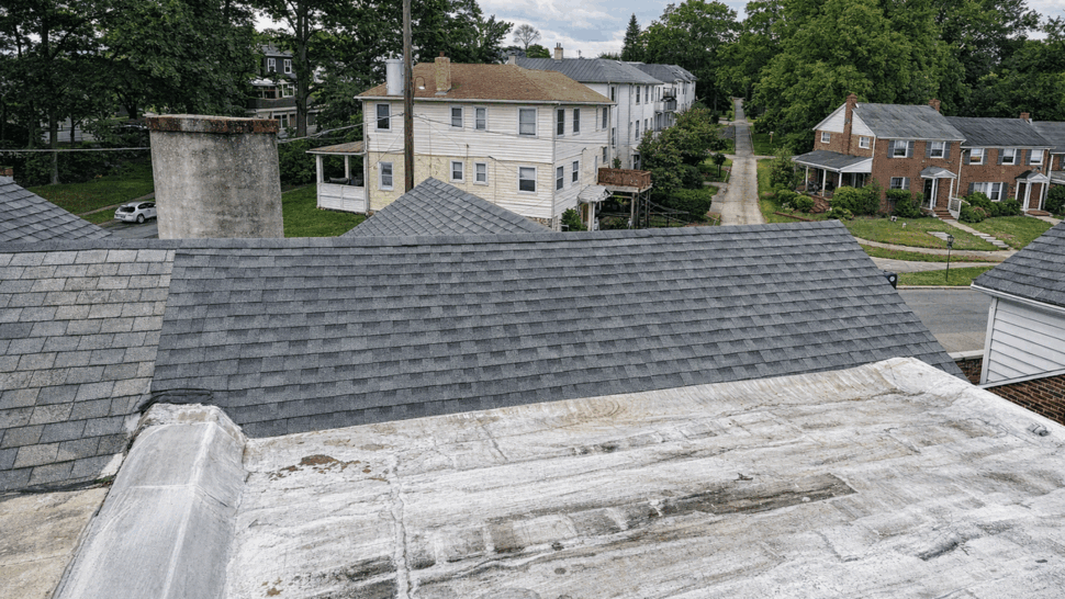 Flat white roof membrane beside a newly shingled gray ridge.