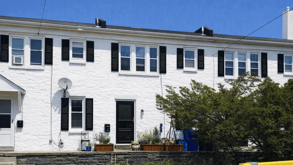 White two-story rowhouse with black shutters, windows and front door