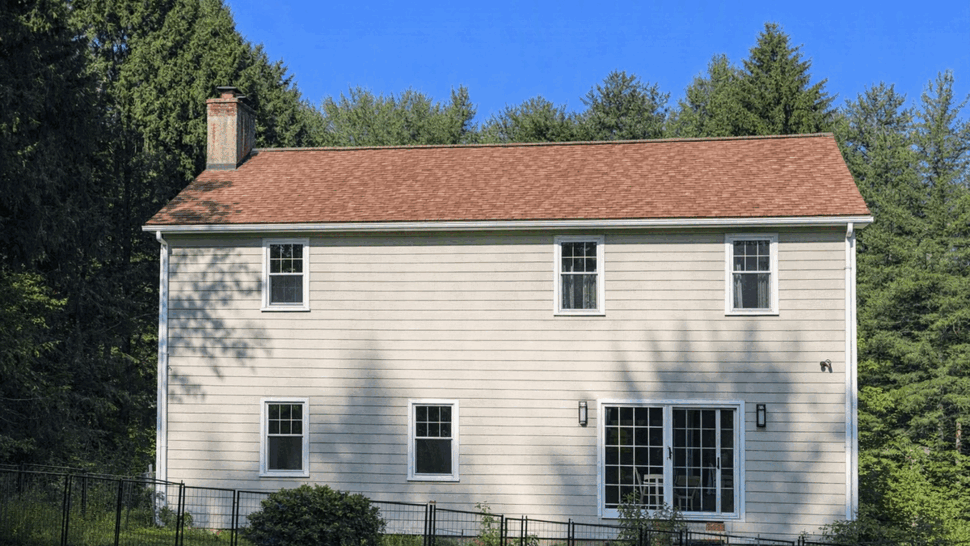 Rear siding with sliding doors and windows | Tycos Roofing And Siding Inc Rear view of house with sliding glass doors, multiple windows and light siding.
