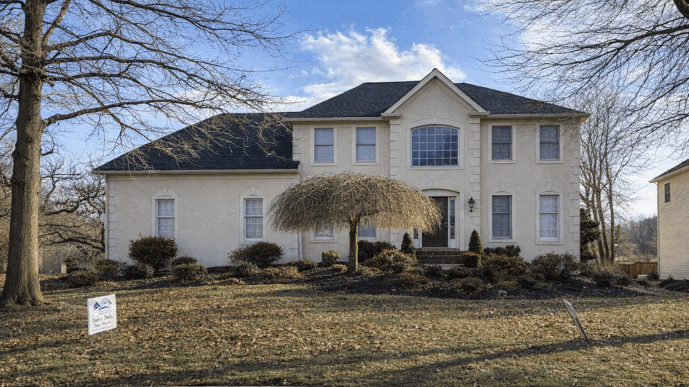 Front view of a two-story house with dark roof and landscaped yard.