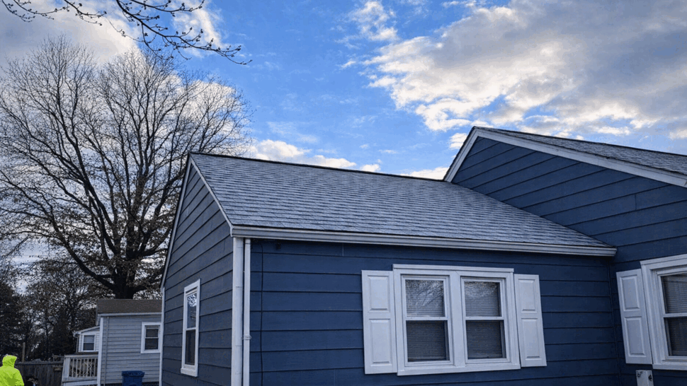 Blue Home Roof and Siding | Tycos Roofing And Siding Inc Blue-sided home with gray shingle roof and white-trimmed windows.