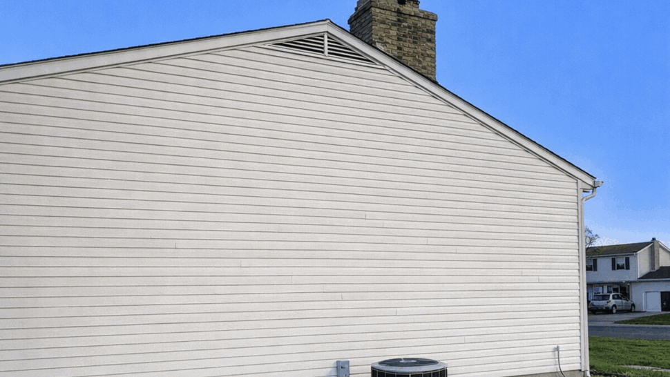 Side view of house with vinyl siding, air conditioner unit and chimney