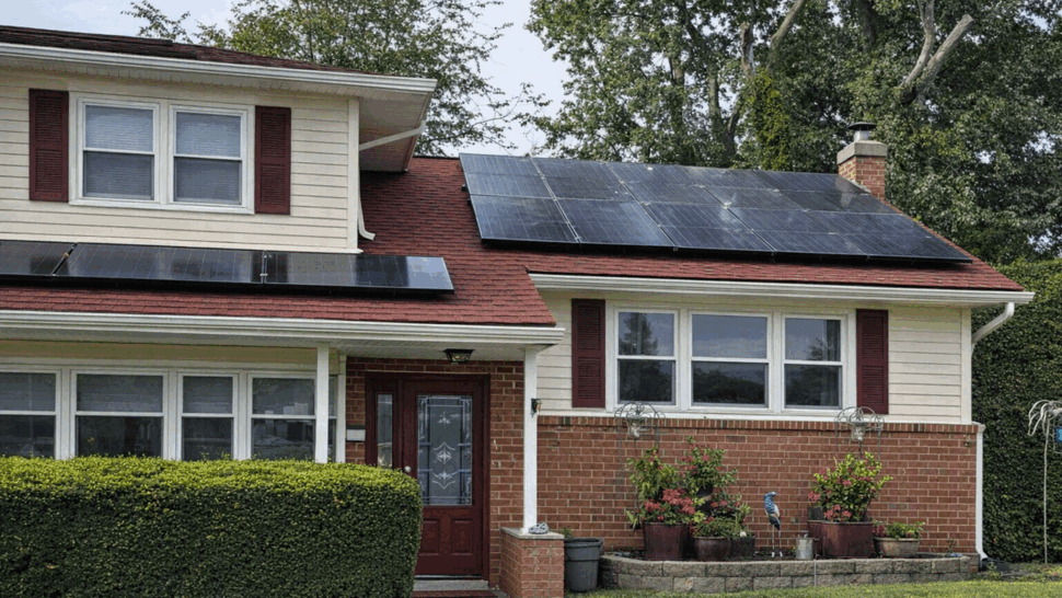 Front entry with red double door, brick facade, shutters and roof solar panels.