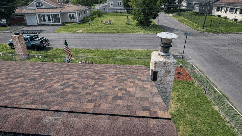 Shingle roof with a chimney cap seen from above looking toward the street.