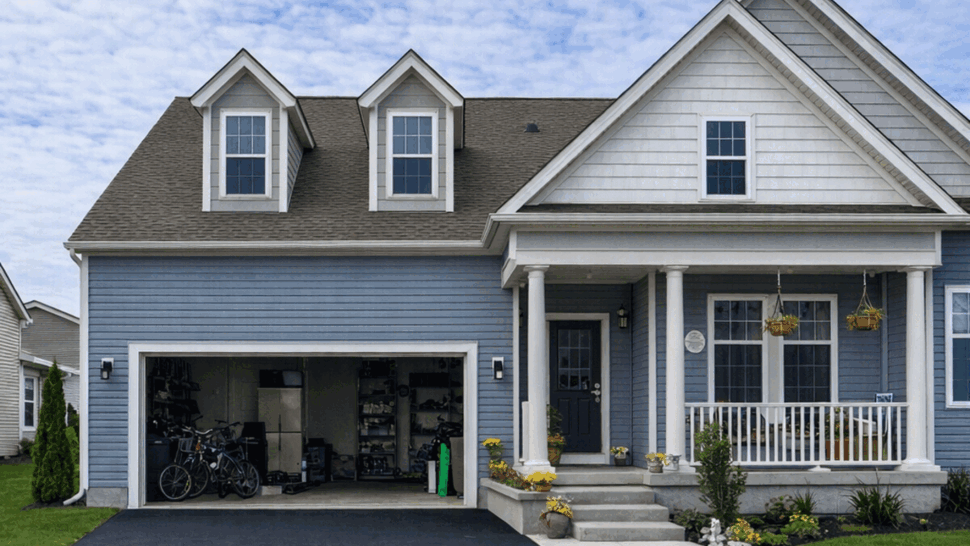 Blue single-family home with white trim, open garage and front porch