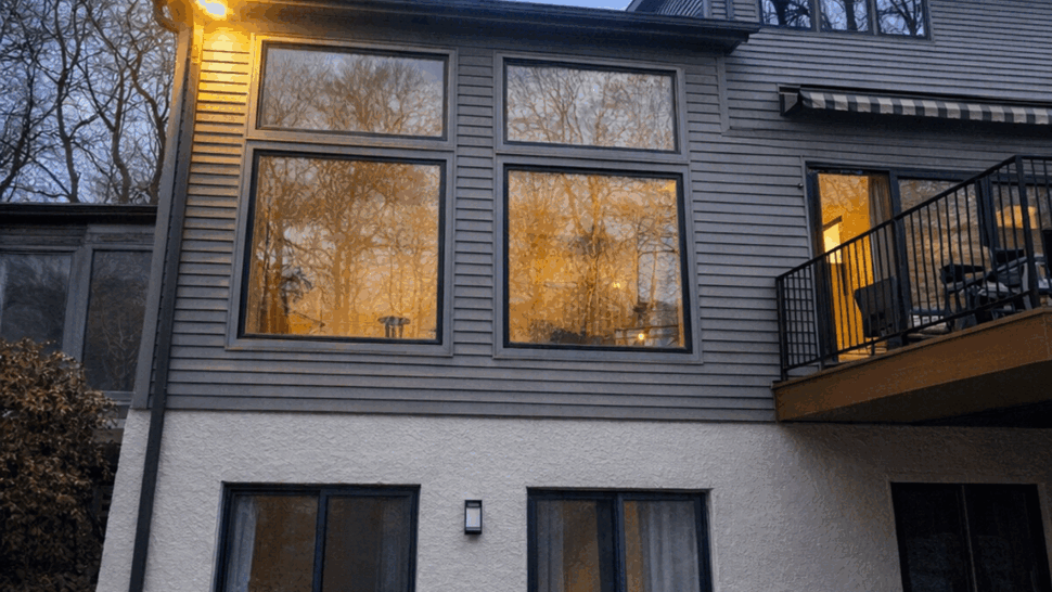 Two-story rear elevation with large windows and a deck at dusk