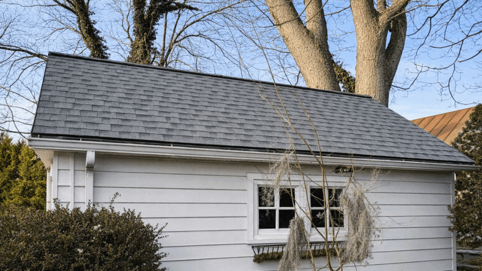 Detached garage roof with shingles and a white downspout gutter