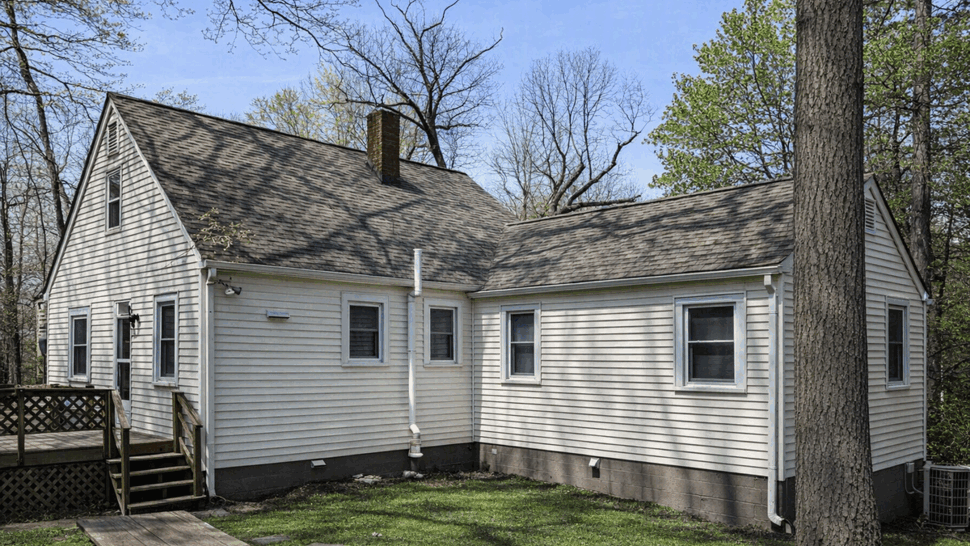 Rear view of house showing roofline, downspout and small deck area