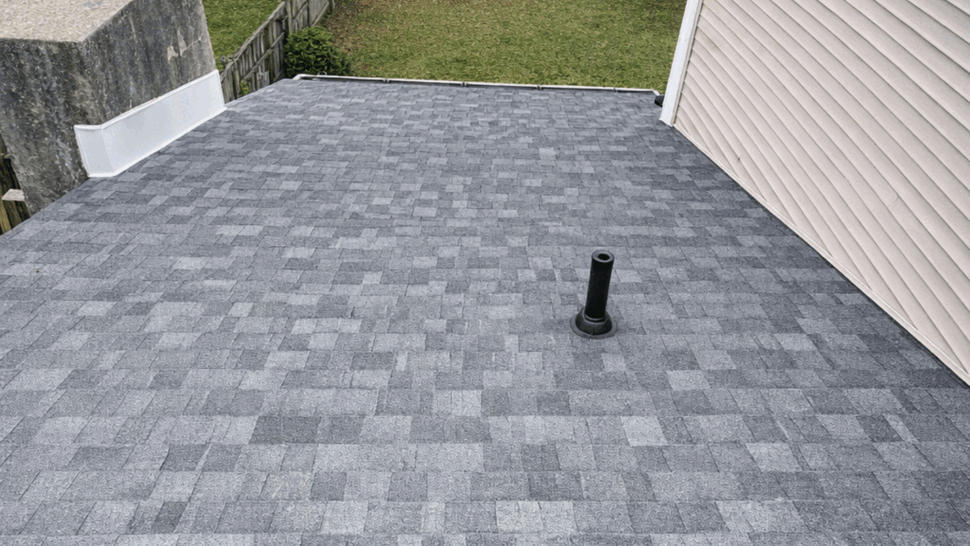 Low-Slope Roof Installation | Tycos Roofing And Siding Inc Gray low-slope shingle roof with vent pipe, chimney, and ridge ventilation