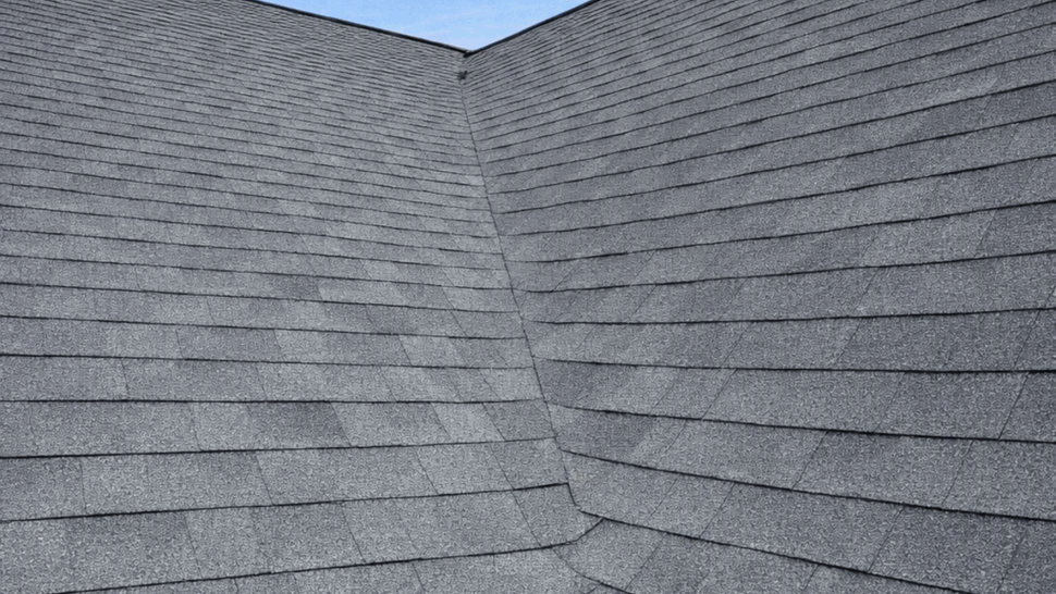 Roof valley with overlapping shingles and a metal gutter at the eave.