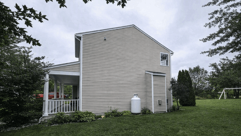 Side Gutter and Downspout View | Tycos Roofing And Siding Inc Side elevation of house with gutters, downspout, propane tank and small porch