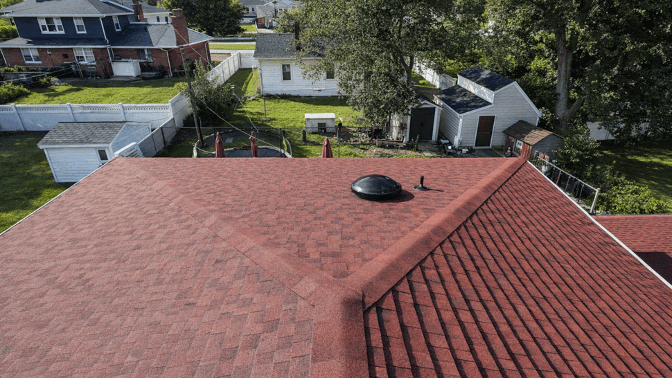 Aerial view of red shingle roof showing ridge, valley and a roof vent.