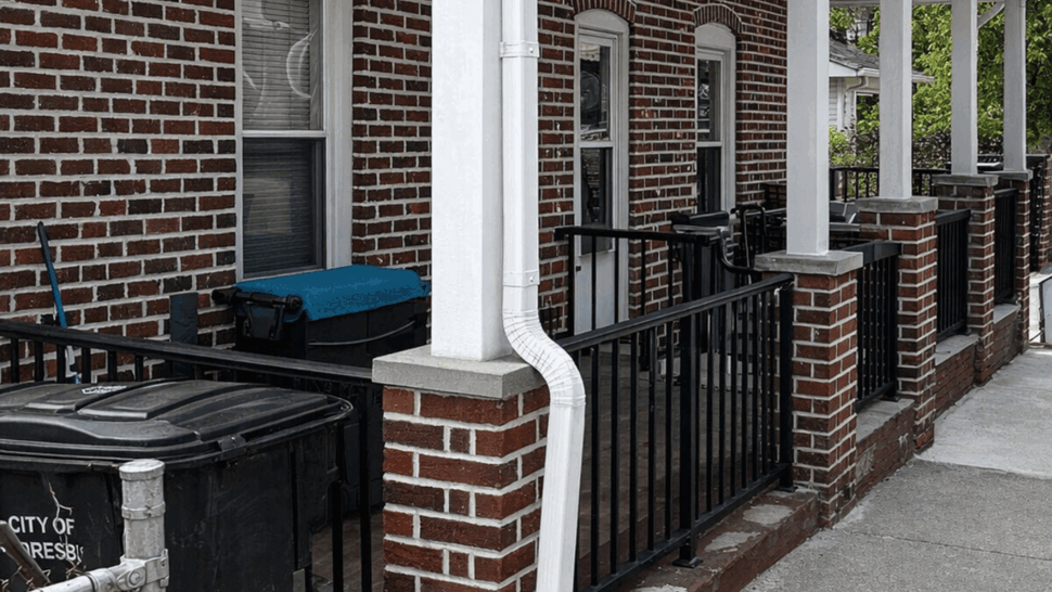 Front porch with white gutter and curved downspout directing water away.