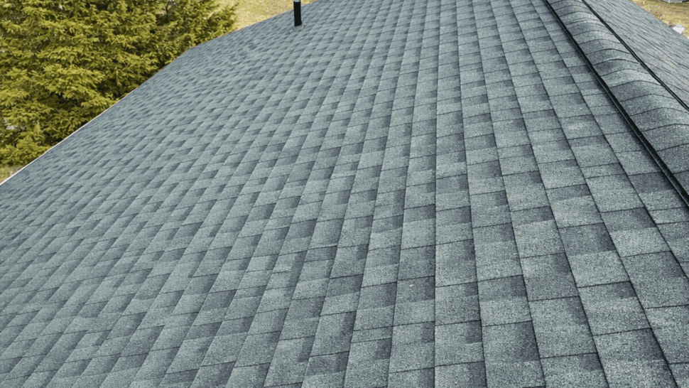 Angled view along a long roof ridge showing green shingle pattern.