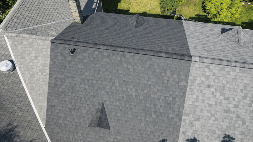 Aerial grey shingle roof | Tycos Roofing And Siding Inc Aerial view of a large grey shingle roof with a darker replaced section visible.