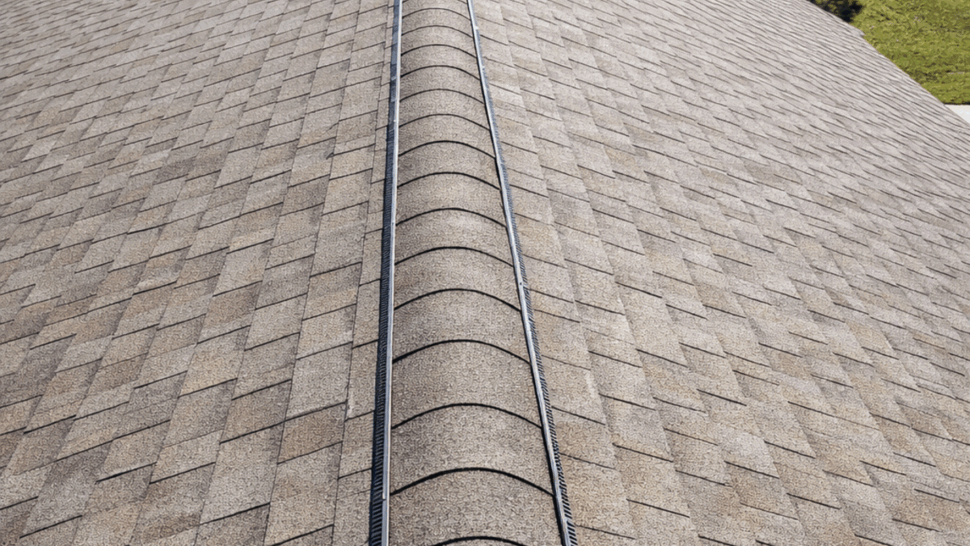 View along roof ridge showing installed ridge vent and asphalt shingles.